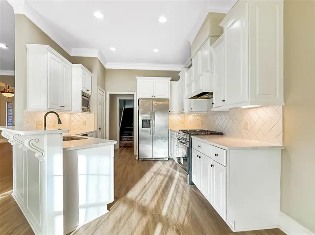 a kitchen with stainless steel appliances granite countertop a stove top oven a sink dishwasher and a refrigerator with wooden floor