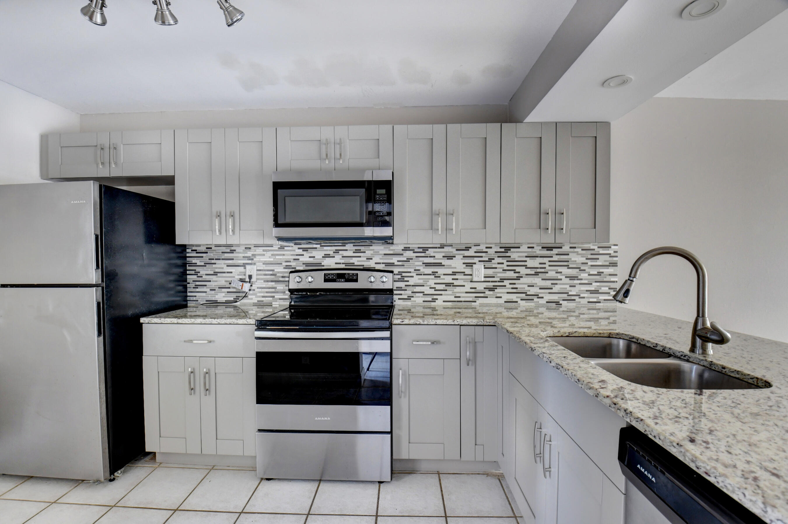 14 Royal Palm Way, Unit 2050 Boca Raton, FL 33432 - Photo 20 of 44 a kitchen with granite countertop a sink stainless steel appliances and white cabinets