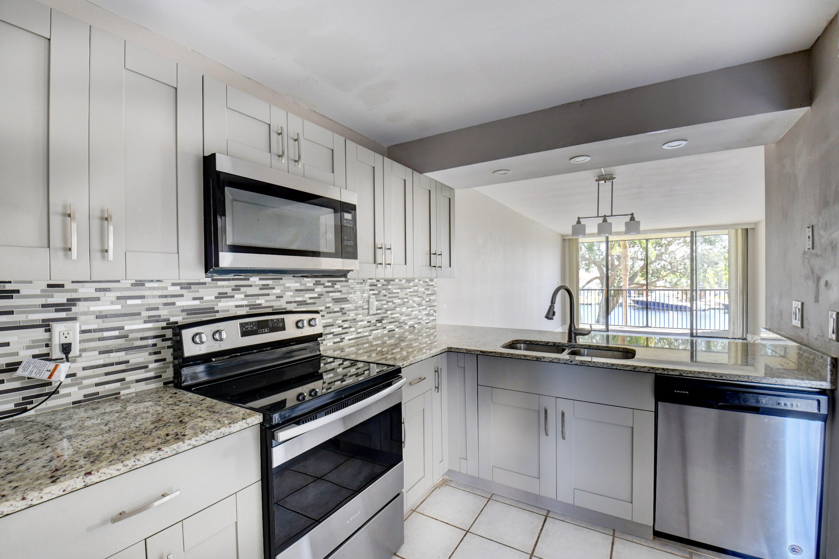 14 Royal Palm Way, Unit 2050 Boca Raton, FL 33432 - Photo 21 of 44 a kitchen with stainless steel appliances a stove sink microwave and cabinets