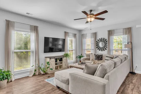 a living room with furniture a flat screen tv and a large window