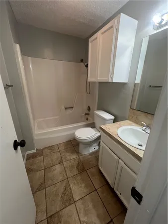 a bathroom with a granite countertop toilet sink and mirror