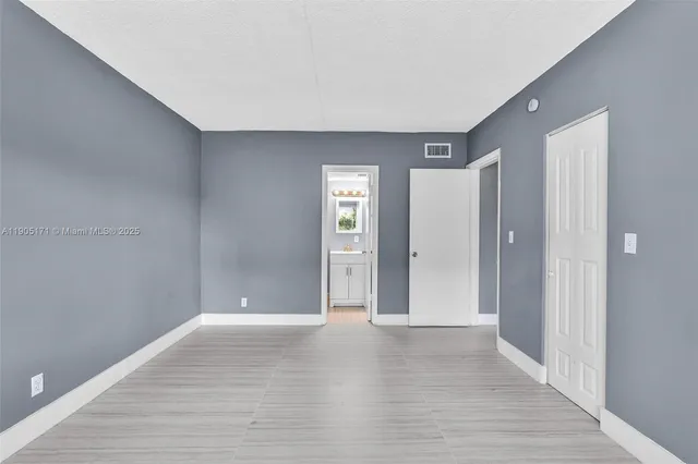 a view of an empty room with wooden floor and closet