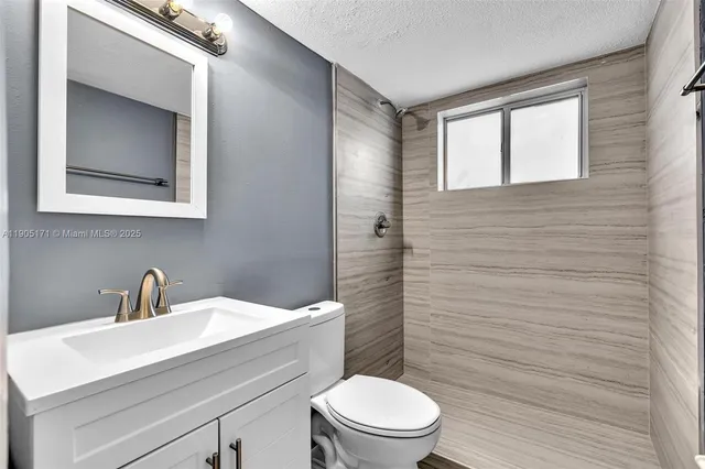 a bathroom with a toilet a sink a mirror and vanity