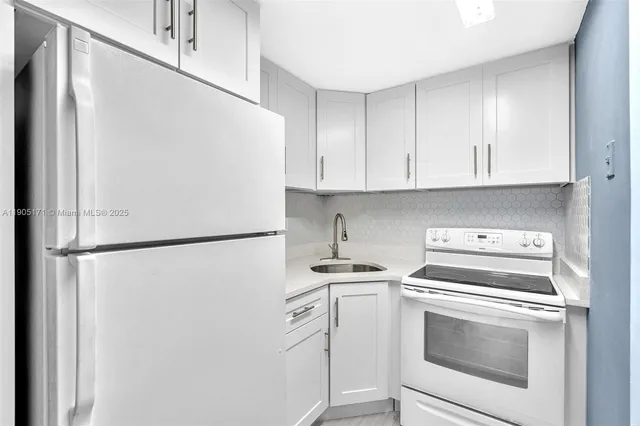a white refrigerator freezer and a stove sitting inside of a kitchen with stainless steel appliances wooden floor