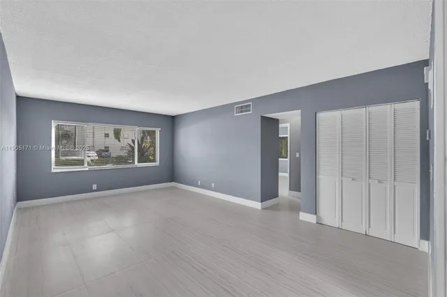 a view of an empty room with wooden floor and window