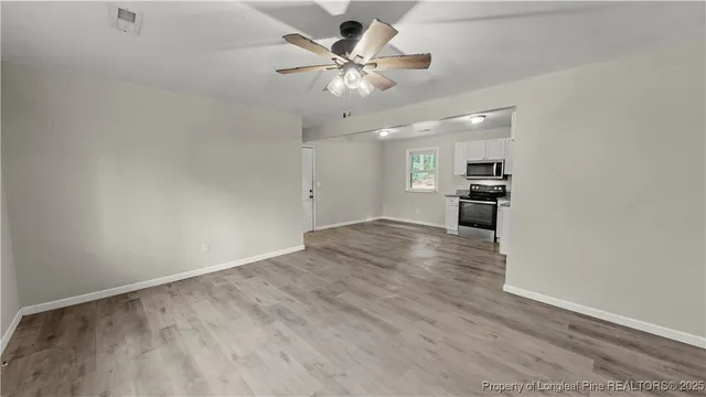 an empty room with wooden floor and a ceiling fan