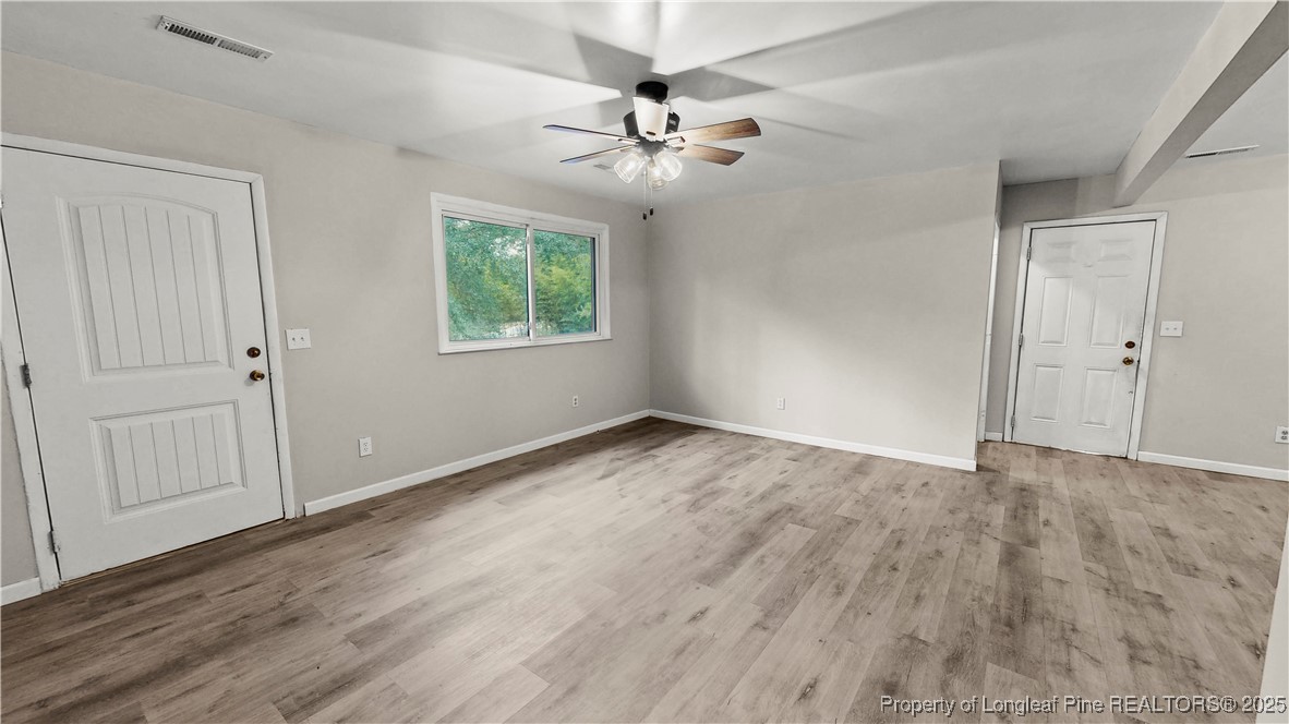 164 Happy Valley Road West End, NC 27376 - Photo 5 of 17 an empty room with wooden floor chandelier fan and windows