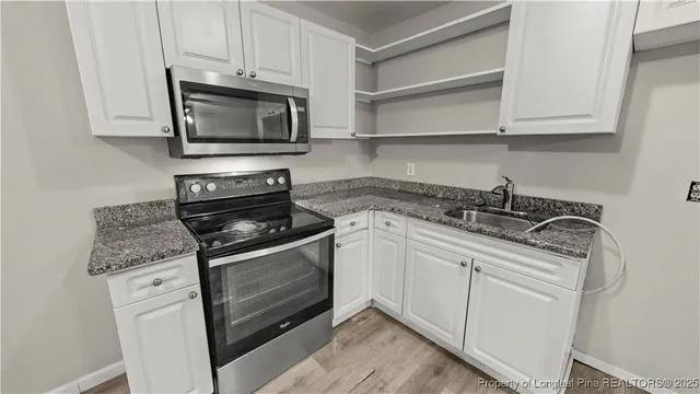 a kitchen with granite countertop white cabinets stainless steel appliances and a sink