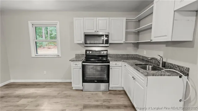 a kitchen with granite countertop a sink a stove and cabinets