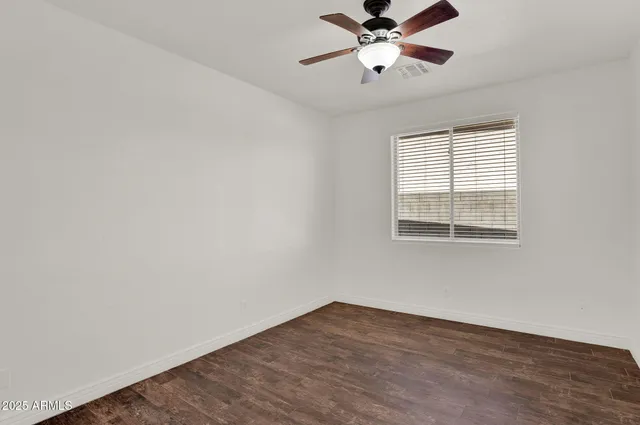 a view of an empty room with a window and wooden floor