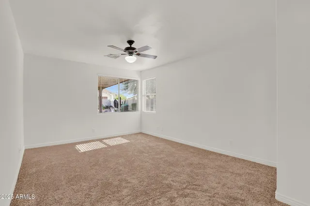 an empty room with windows and chandelier fan