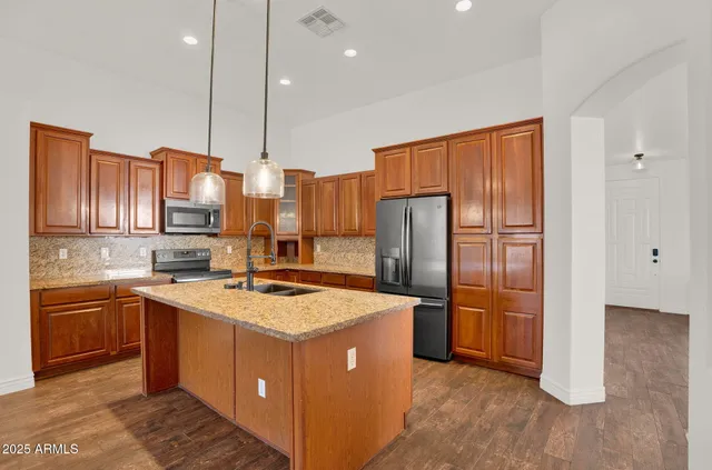 a kitchen with stainless steel appliances granite countertop a sink a stove and a refrigerator