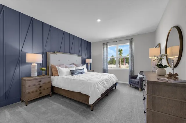 a bedroom with bed a mirror on dresser and a window