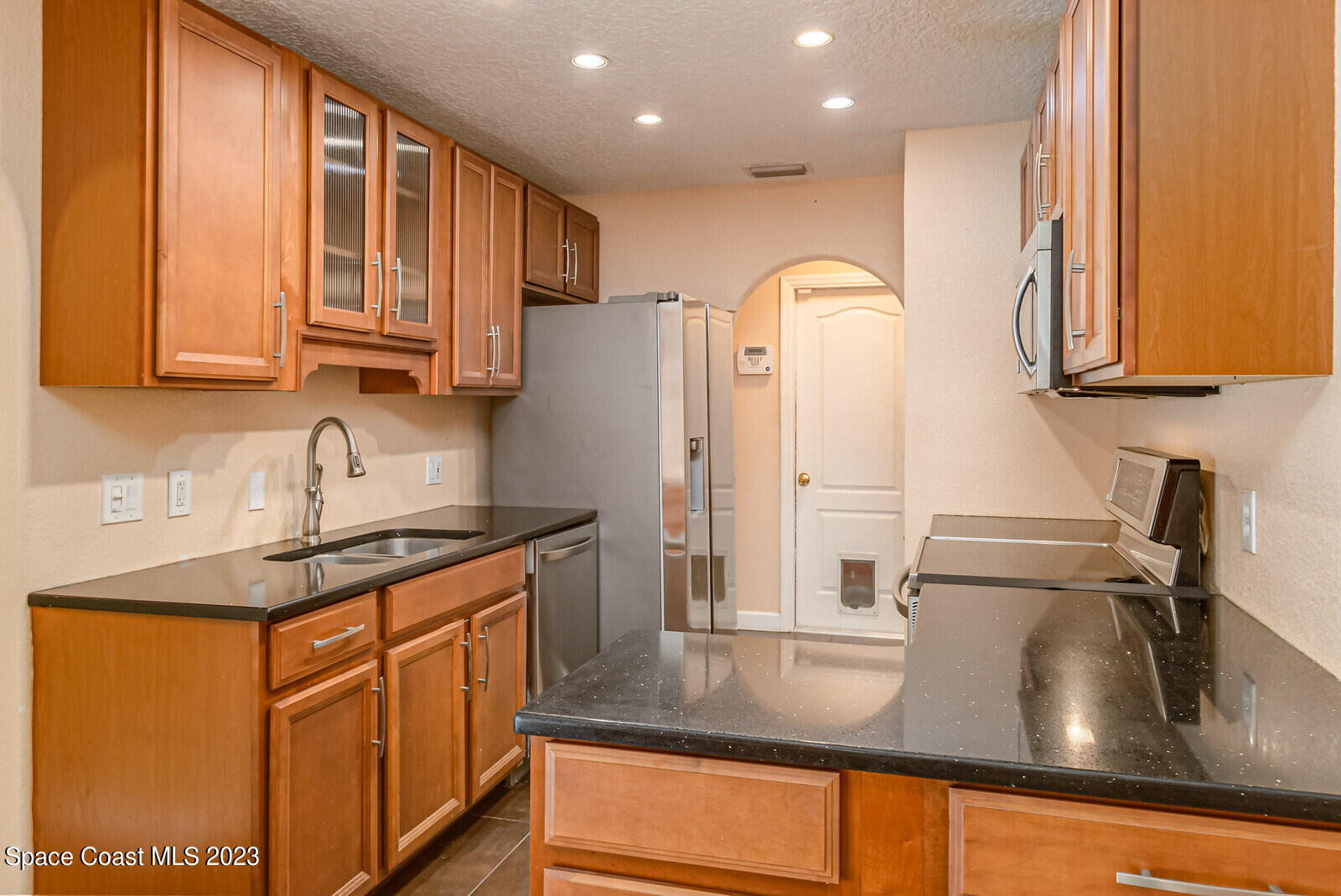2567 Wright Avenue Melbourne, FL 32935 - Photo 5 of 36 a kitchen with stainless steel appliances granite countertop a sink refrigerator and cabinets