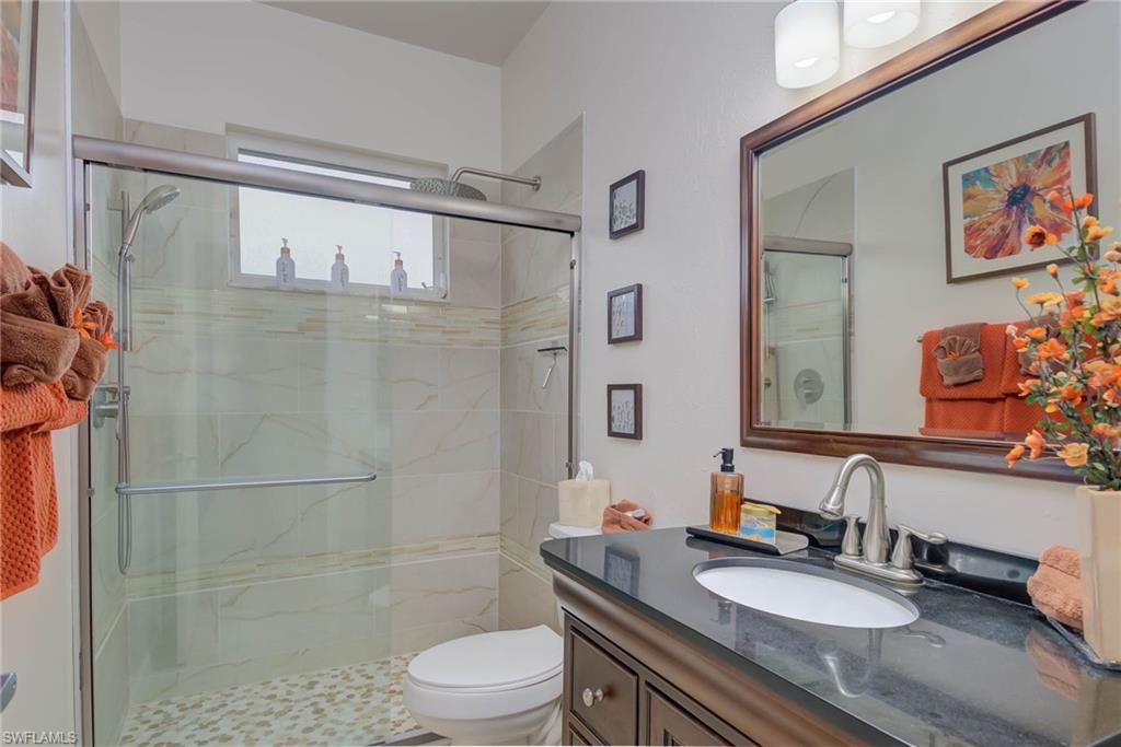 18370 Tulip Road Fort Myers, FL 33967 - Photo 19 of 30 a bathroom with a granite countertop sink a mirror a toilet and shower