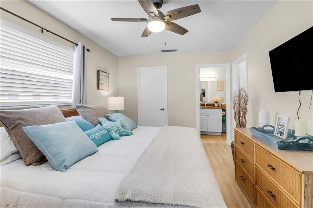 3325 Airport Road North, Unit G5 Naples, FL 34105 - Photo 4 of 8 Bedroom with light wood-style flooring, ceiling fan, connected bathroom, and a textured ceiling
