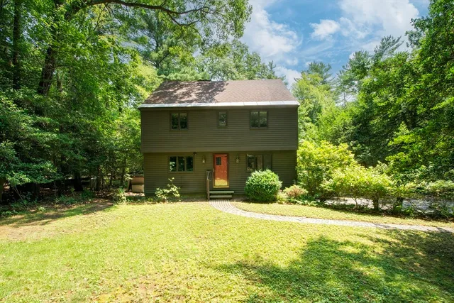 a front view of house with yard and trees in the background