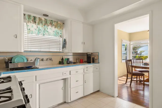 a kitchen with granite countertop white cabinets white appliances a sink and a window