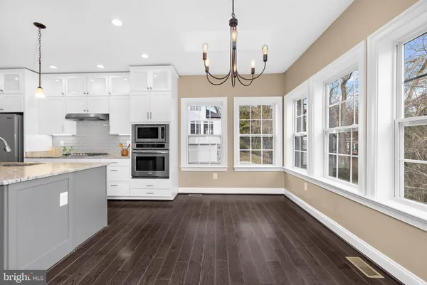 a large kitchen with stainless steel appliances granite countertop a large window oven a sink and dishwasher a oven with wooden floors