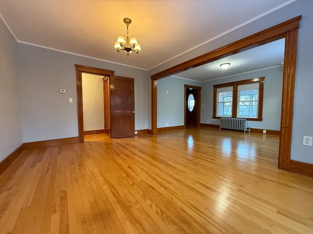 a view of a room with wooden floor and a chandelier