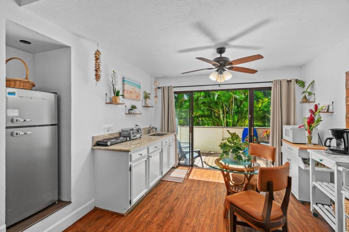 4480 Ka Haku Road, Unit 105 Princeville, HI 96722 - Photo 7 of 25 a kitchen with stainless steel appliances a stove a refrigerator a sink dishwasher and a dining table with wooden floor