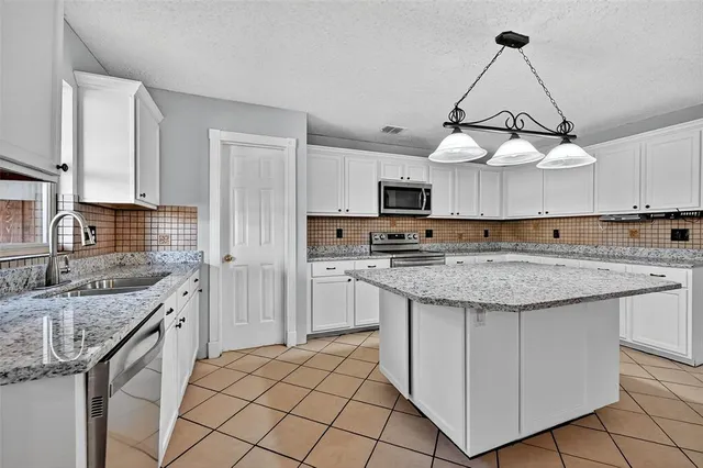 a kitchen with kitchen island granite countertop a sink a stove oven a counter top space and cabinets