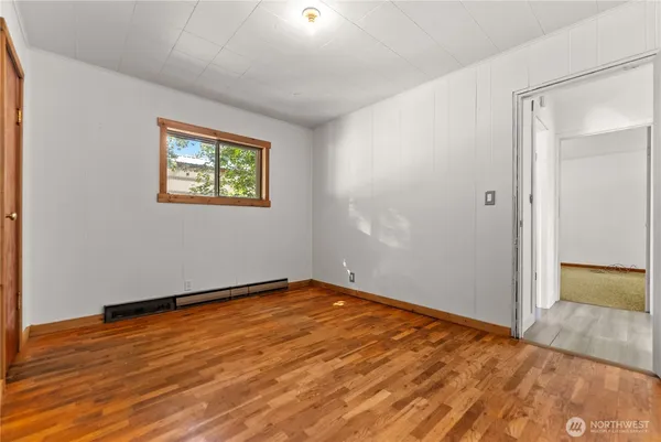 an empty room with wooden floor and window