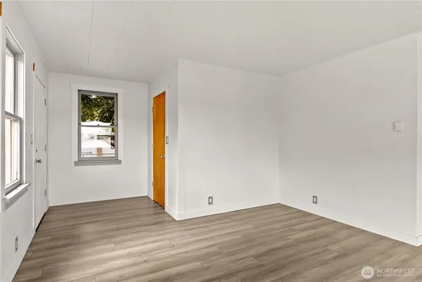 a view of an empty room with wooden floor and a window