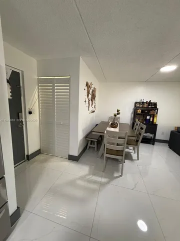 a living room with furniture a flat screen tv and a refrigerator