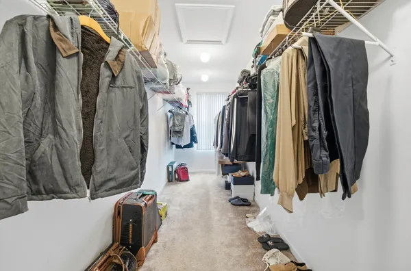 a view of walk in closet with clothes and shoes