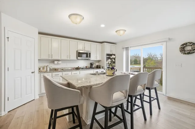 a kitchen with kitchen island granite countertop a dining table chairs and white cabinets