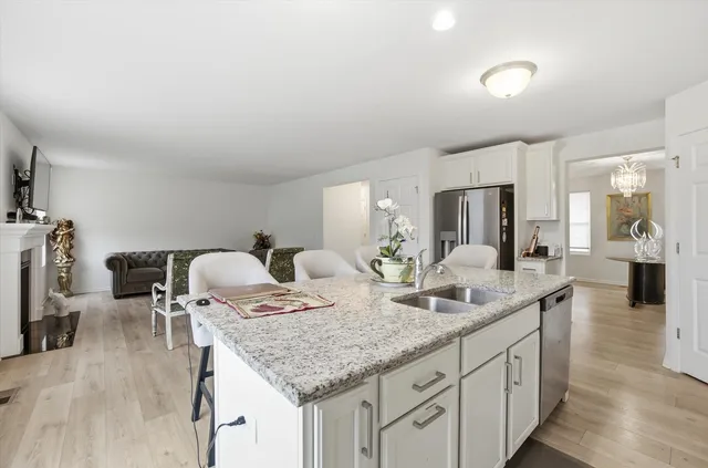 a kitchen with granite countertop kitchen island stainless steel appliances a sink and a refrigerator
