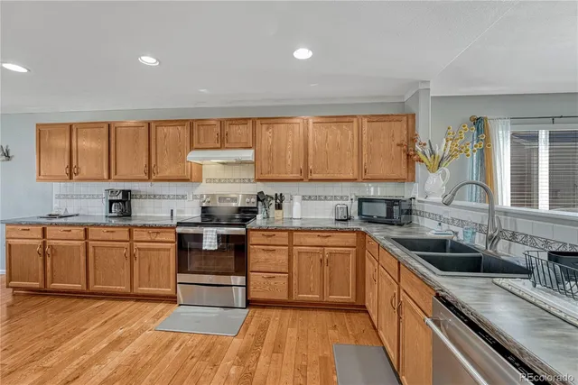 a kitchen with stainless steel appliances granite countertop wooden cabinets and a stove top oven