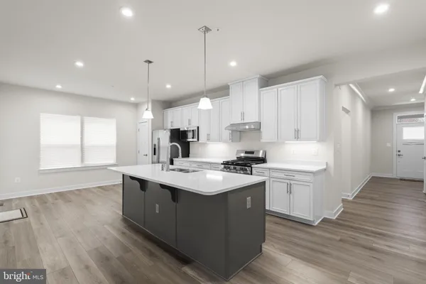 a kitchen with stainless steel appliances granite countertop a sink a stove and a wooden floors