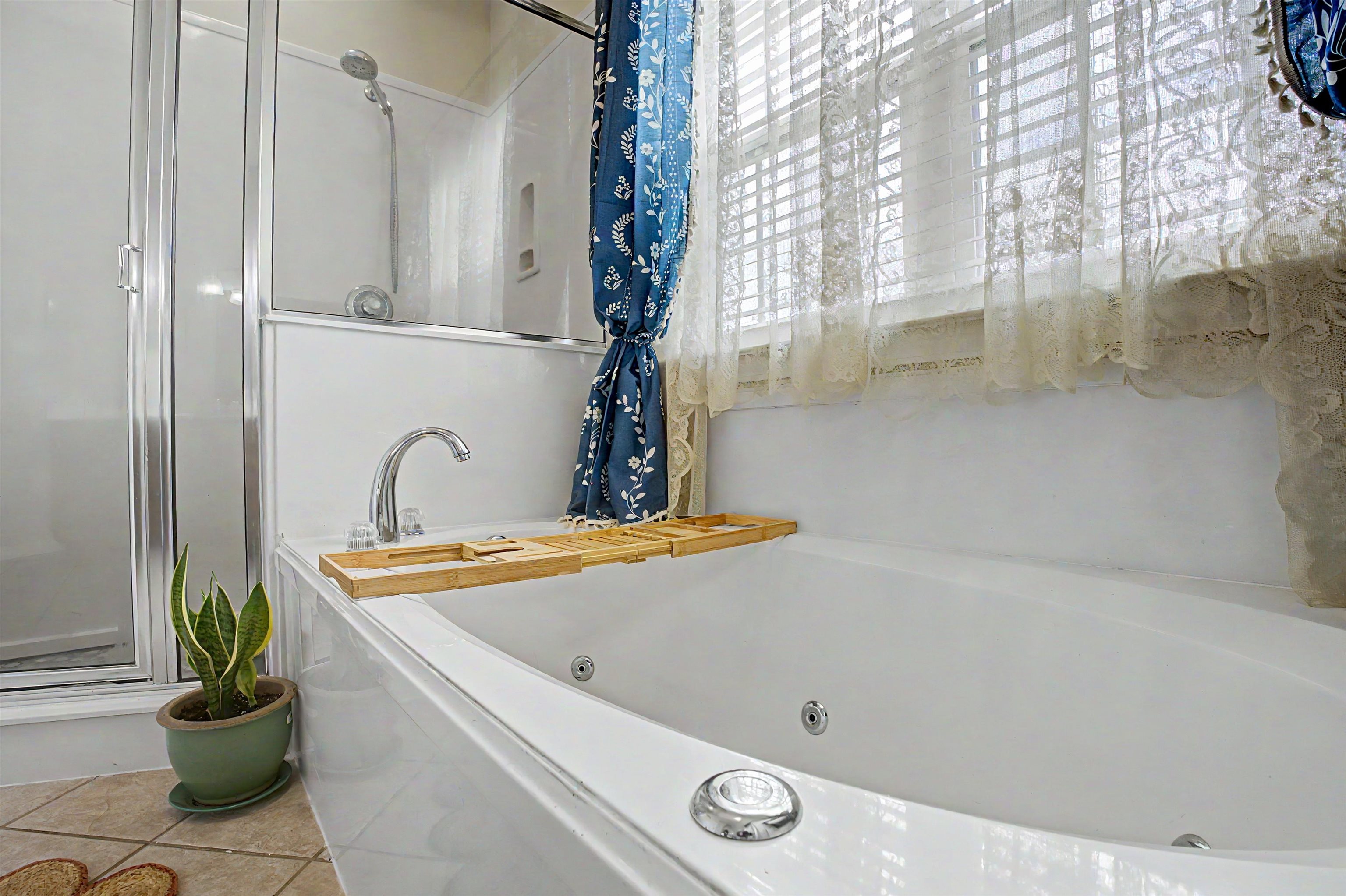 134 Rembert Drive Atoka, TN 38004 - Photo 26 of 38 White jetted tub with chrome fixtures and an adjacent glass-enclosed shower