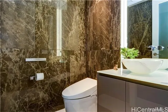 a bathroom with a granite countertop sink and a toilet