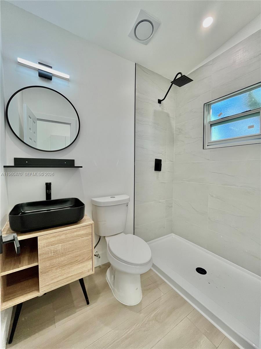 6241 Northwest Miami Place Miami, FL 33150 - Photo 30 of 33 a bathroom with a sink a toilet a mirror and shower