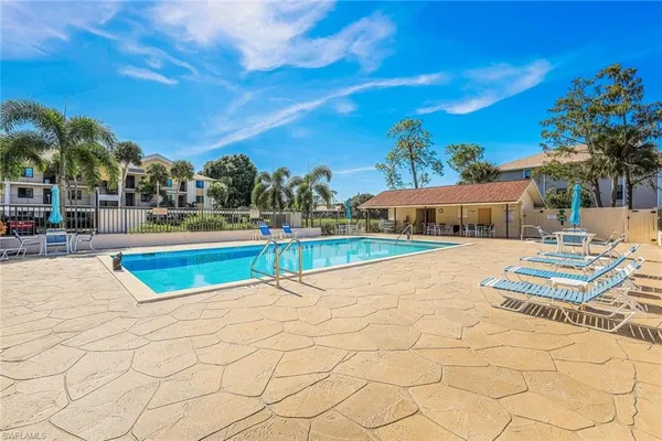 a view of swimming pool with lounge chair and dinning table under an umbrella
