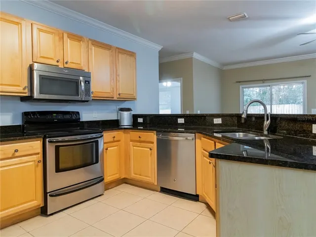 a kitchen with granite countertop a sink a stove top oven a granite counter space and a window