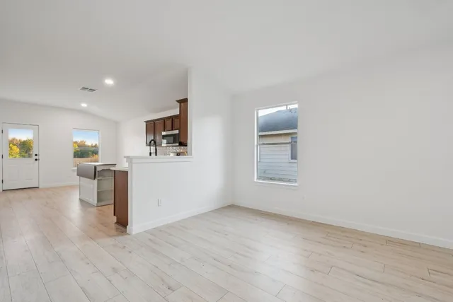 an empty room with wooden floor and windows