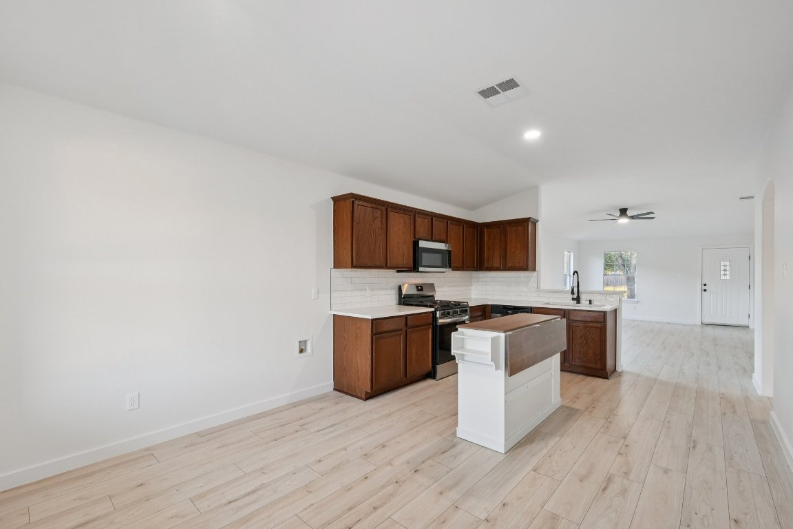 17921 Basket Flower Bend Elgin, TX 78621 - Photo 15 of 40 a kitchen with stainless steel appliances granite countertop a stove top oven a sink dishwasher and a refrigerator with wooden floor