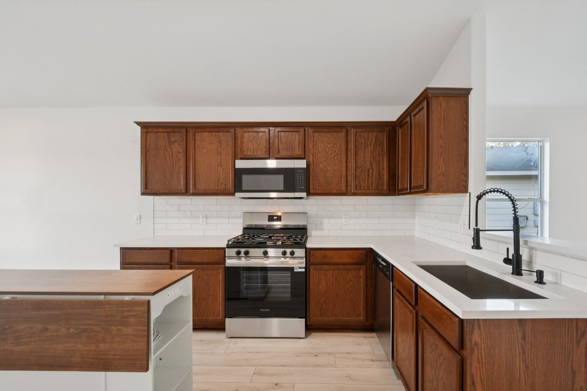 17921 Basket Flower Bend Elgin, TX 78621 - Photo 19 of 40 a kitchen with stainless steel appliances granite countertop a sink stove and microwave