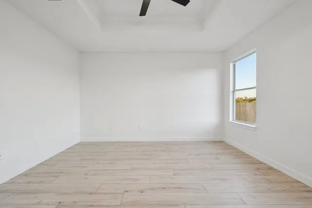 a view of an empty room with a window and wooden floor