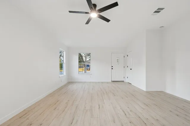 an empty room with a window and ceiling fan