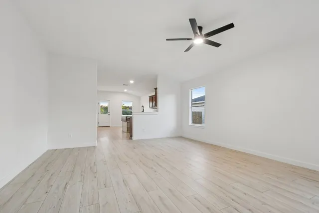 a view of empty room with wooden floor and ceiling fan