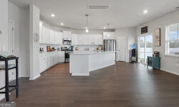 a kitchen with stainless steel appliances granite countertop a sink a refrigerator a stove a microwave and white cabinets