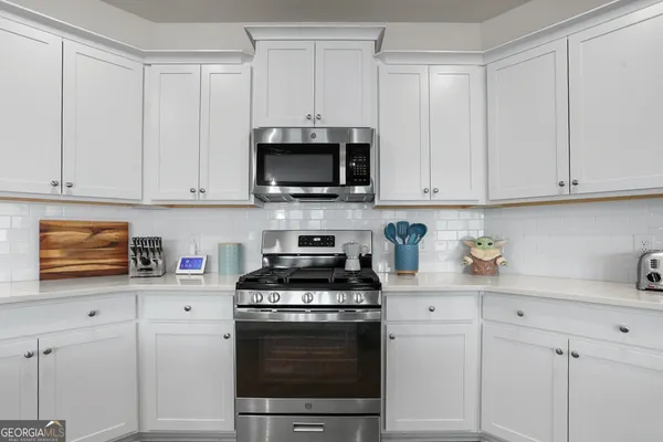 a kitchen with stainless steel appliances granite countertop a stove a white cabinets and a sink