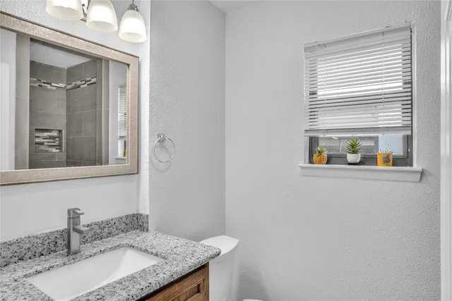 a bathroom with a granite countertop sink and a mirror