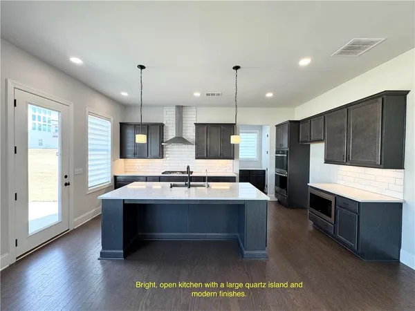 a kitchen with stainless steel appliances kitchen island granite countertop a sink a stove and a wooden floors