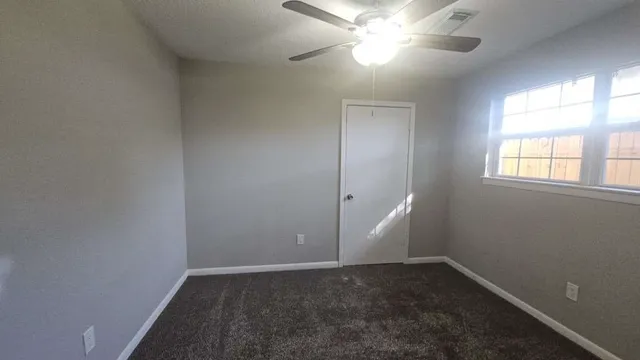 an empty room with a window and a fan